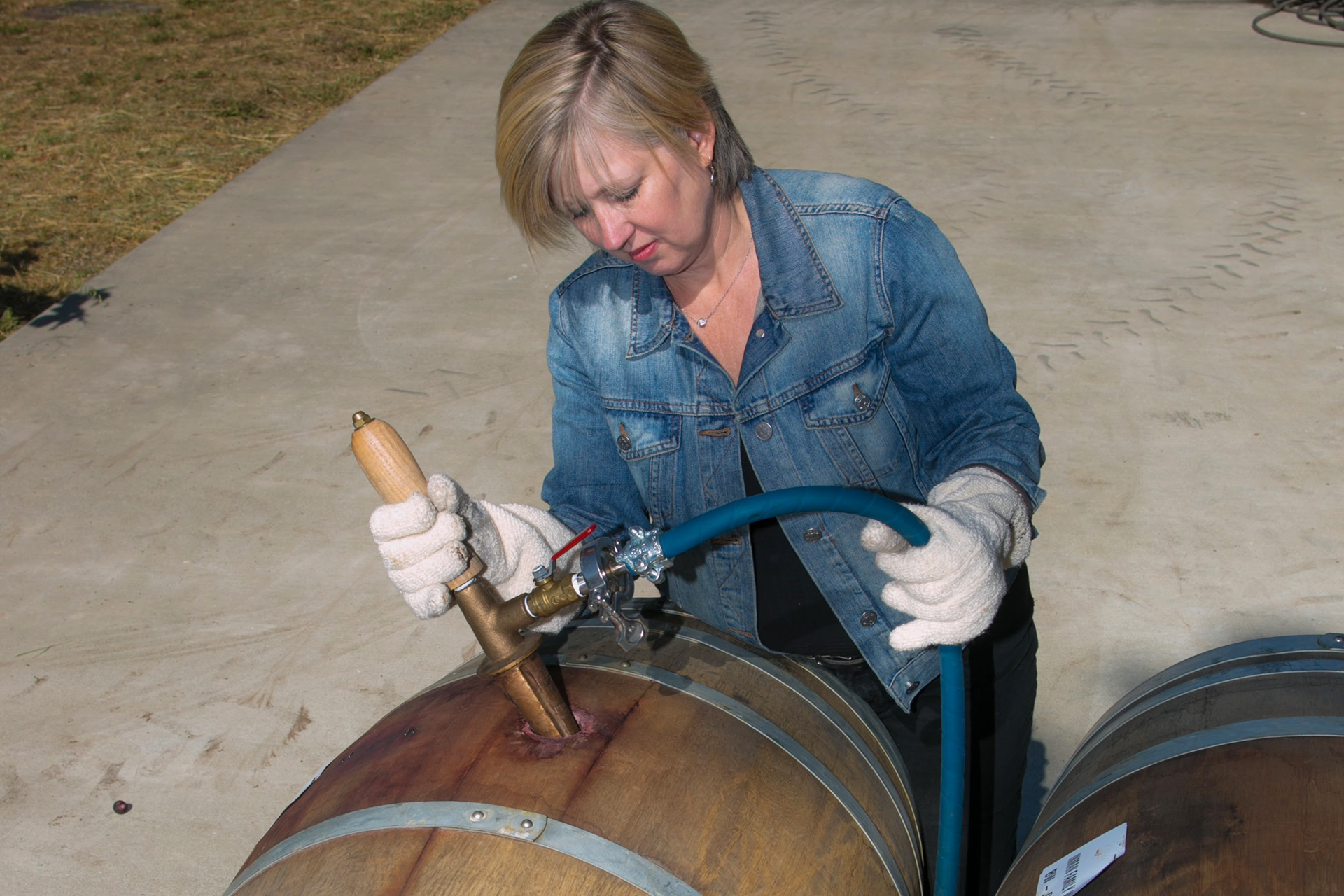 Owner and winemaker Kathleen Inman taking a sample of wine from a barrel
